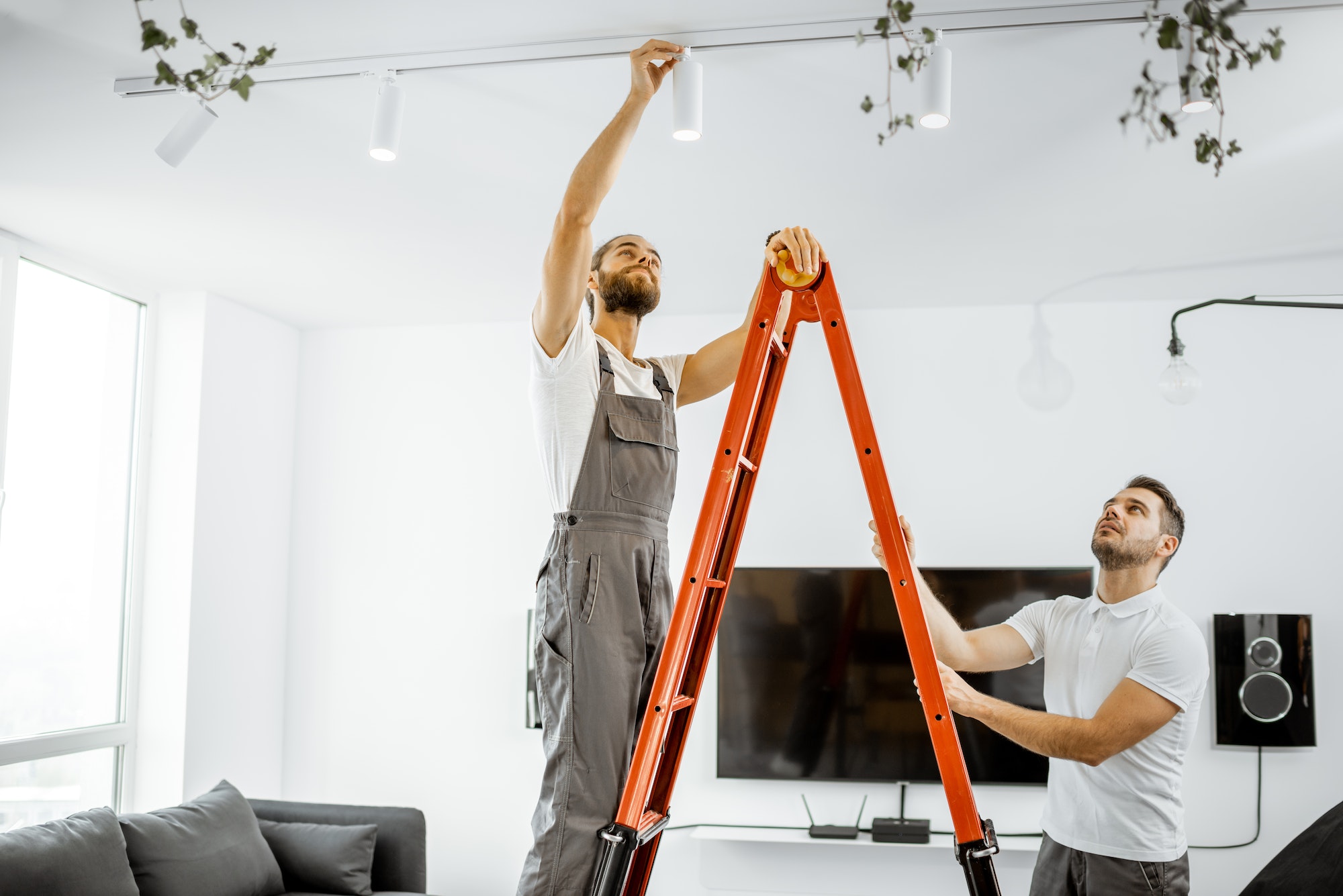 Hombres con escalera al techo instalando luces en casa