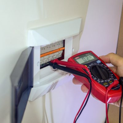 un electricista está reparando un panel eléctrico. reparacion electrica medición de tensión de red