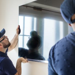 Personas haciendo montaje de televisor en la pared