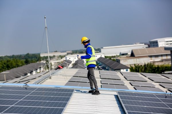 Instalador de paneles solares instalando paneles solares en el techo del almacén utilizando implementos de proteccion